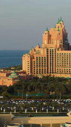 a very tall building sitting on top of a lush green field next to the ocean