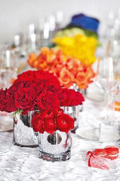 a vase filled with purple and white flowers sitting on top of a table next to wine glasses