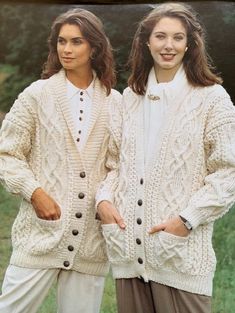 two women standing next to each other wearing sweaters and pants with buttons on them