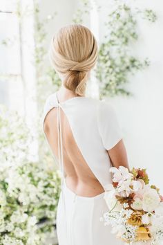 the back of a woman's dress holding a bouquet