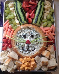 a metal tray filled with fruit and veggies next to a face made out of bread