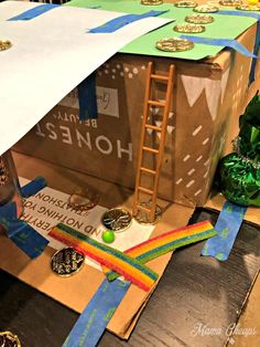 an open cardboard box with ribbons and medals on the floor next to a ladder that is attached to it