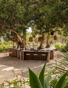 an outdoor dining table surrounded by trees and chairs