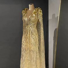 Golden Elegance: The gold hue exudes opulence and regal charm, ensuring you make a memorable and stylish statement. Sparkly Beaded Cape: The cape with sparkly bead embellishments adds a touch of glamour and sophistication, enhancing the gown's allure. Ideal for Wedding Parties: Tailored for wedding parties, ensuring you exude charm and grace amidst the celebration. Perfect for Formal Events: Equally fitting for various formal occasions, making it a versatile addition to your formal wardrobe. Lux Gold Beaded Dress, Beaded Cape, Alternative Bridal, High Fashion Outfits, Evening Dresses Short, Evening Dresses Plus Size, Ball Gowns Evening, Formal Party Dress, Wedding Parties