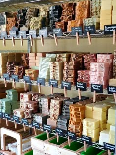 many different types of soaps are on display in a store with wooden pegs