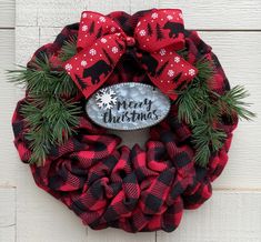 a red and black christmas wreath hanging on the side of a building