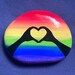 a rainbow colored rock with a heart in the middle and mountains on it's side