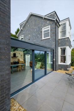 a house that is made out of stone and has glass doors leading to the outside