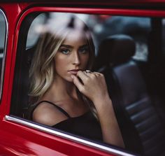 a beautiful blond woman sitting in a red car