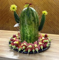 a cactus made out of fruits and vegetables on a plate with flowers in the middle