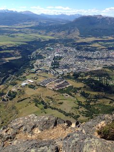 a view from the top of a mountain looking down on a city and mountains in the distance