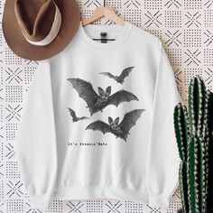 It's Freakin' Bats Halloween Sweatshirt | Fall Crewneck | Bat Sweatshirt  Perfect for Halloween and the Fall season! For a wider selection of Halloween Sweatshirts, Hoodies, T-shirts and Totes please click on the link here -> https://etsy.me/3BTvj5M It's Freakin' Bats Sweatshirt Details: * Unisex Cotton Blend Crewneck Sweatshirt * Loose Fit  * Pre-Shrunk  * Machine Washable  * Unisex Fit - Refer to sizing guide in photos for sizes - If you would like an oversized fit, size up 1 or 2 sizes.   Care Instructions *PLEASE READ*  * Cold machine wash only on a gentle cycle with similar colours - wash garment inside out  * Use standard washing powder only; it is not recommended that fabric softeners be used as they may strip the coloured ink * If ironing is necessary, iron inside-out on the lowest Halloween White Screen Print Sweatshirt, White Grunge Tops For Halloween, Bat Sweatshirt, Bat Shirt, Fall Crewneck, Bats Halloween, Sweatshirt Details, Embroidery Sweater, Halloween Sweater