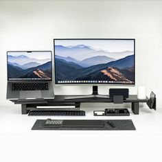 two computer monitors sitting next to each other on top of a desk in front of a laptop