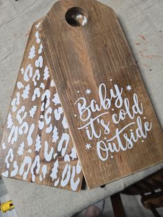 two wooden tags that say baby it's cold outside and one with snowflakes on them