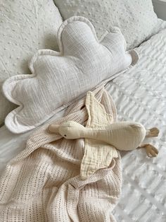 two stuffed animals laying on top of a white bed next to pillows and blankets in the shape of hearts