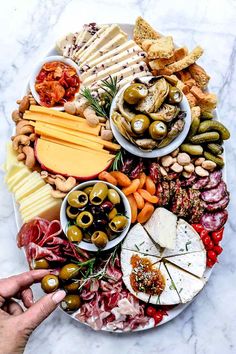 a platter filled with different types of cheeses, meats and olives