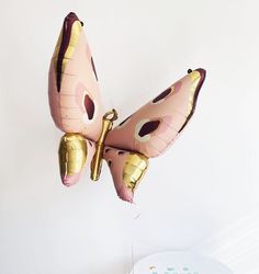 a pink and gold balloon shaped like a butterfly on top of a table with a cake