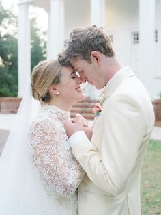 a bride and groom standing in front of a white house