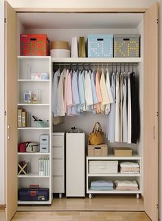 an organized closet with clothes and other items on shelves, including boxes, baskets, and bins