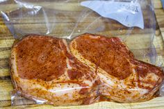 two pieces of meat wrapped in plastic on a cutting board