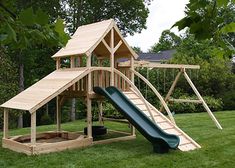 a wooden play set in the grass with a slide and climbing frame attached to it