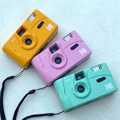 three different colored cameras sitting next to each other