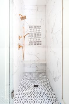 a bathroom with white and black tile flooring, shower head, and hand held shower faucet