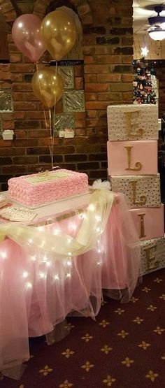 a table topped with lots of pink and gold cake next to balloons in the air