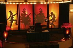 the stage is set up for an event with silhouettes on it and flowers in vases