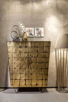 a gold sideboard with two vases on it and a lamp next to it