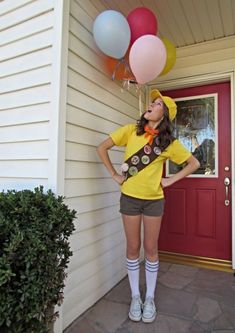 a woman standing in front of a house with balloons attached to her head and legs