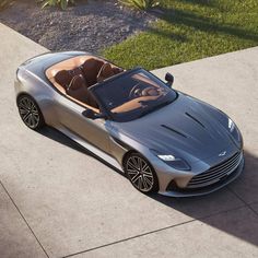 an overhead view of a silver sports car parked on the side of a road with grass and bushes in the background