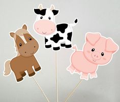 there are three farm animals on sticks in the shape of pigs and cows, one is brown