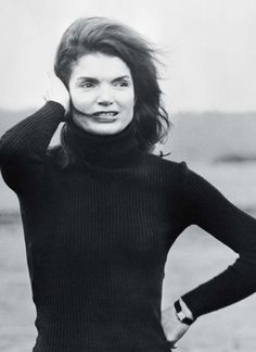 black and white photograph of a woman with her hair in the air, wearing a turtle neck sweater