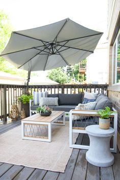 a patio with an umbrella over the couch and table on top of it's wooden deck