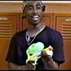 a young man holding a green object in his right hand and smiling at the camera