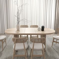 a dining room table with four chairs and a vase on the table in front of it