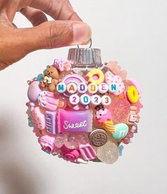 a hand is holding a small ornament that says made in 2013 with various items