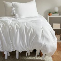 a bed with white sheets and pillows on top of it in a room next to a book shelf