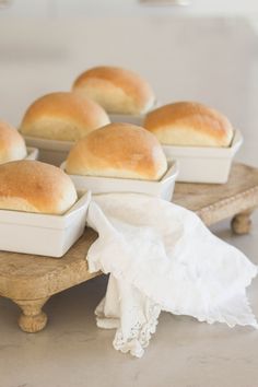 several rolls in white dishes on a wooden tray