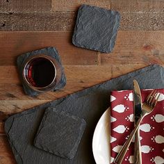 a place setting with napkins, silverware and wine glass on a wooden table