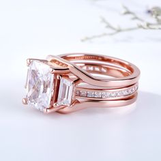 This ring set shimmers with all your beautiful moments to come. It showcases a radiant cut center stone flanked by tapered baguette cut stones while additional round stones line the inner band. Interchangeable style and rose gold tone lend sentimental appeal to the design. All the stones sparkle perfectly from every angle,making the ring an eye-catcher everywhere. Carat Weight: 5.2 ctStone Size: 8*10 mmStone Type: Jeulia® StoneNumber of Stones: 1 Stone Color: Diamond WhiteStone Shape: RadiantCarat Weight: 0.994 ctStone Size: 6*5*3,1.1,1.3,1.5,1.5*1.5 mmStone Type: Jeulia® StoneNumber of Stones: 37 Stone Color: Diamond WhiteStone Shape: Tapered Baguette, Round, PrincessWeight: 10.59 gWidth: 11.65 mmHeight: 7.7 mmThickness: 6 mmMaterial: 925 SilverPlating Color: Rose Gold Square Cut Channel Set Jewelry For Weddings, Wedding Square Cut Channel Set Rings, Wedding Rings With Brilliant Cut Rectangular Stone, Rose Gold Square Cut Wedding Rings, Wedding Diamond Ring With Rectangular Stone And Accent Stones, Rose Gold Channel Set Diamond Ring For Wedding, Wedding Diamond Ring With Rectangular Accent Stones, Sterling Silver Rings Set, Silver Ring Set