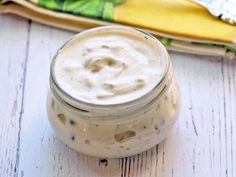 a glass jar filled with food sitting on top of a wooden table next to a spoon