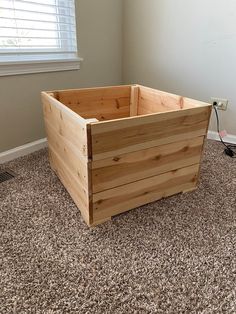 a wooden box sitting on top of a carpeted floor in front of a window