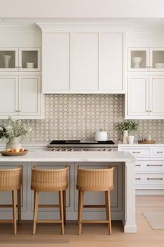 two stools sit at the center of a kitchen island in front of white cabinets