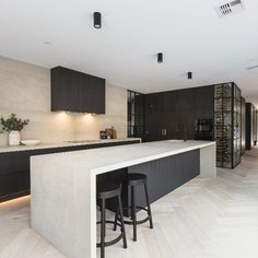 a kitchen with two stools next to an island in the middle of the room