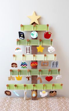 a christmas tree made out of wooden pegs and magnets on a shelf with an ornament hanging from the top