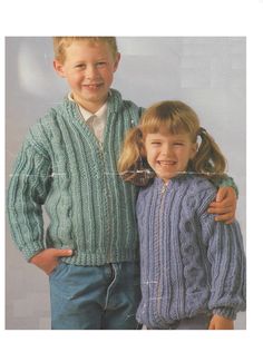 two children in sweaters and jeans posing for a photo with their arms around each other