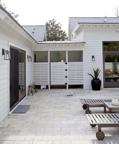 an outdoor patio area with benches and potted plants on the side of the house