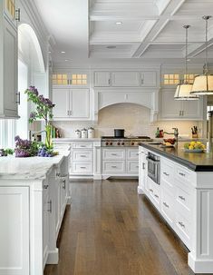 a large kitchen with white cabinets and wood floors